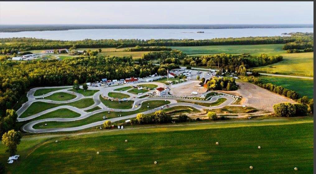 Aerial photograph of USAir Motorsports Raceway, its road course looping through green fields with Shawano Lake behind